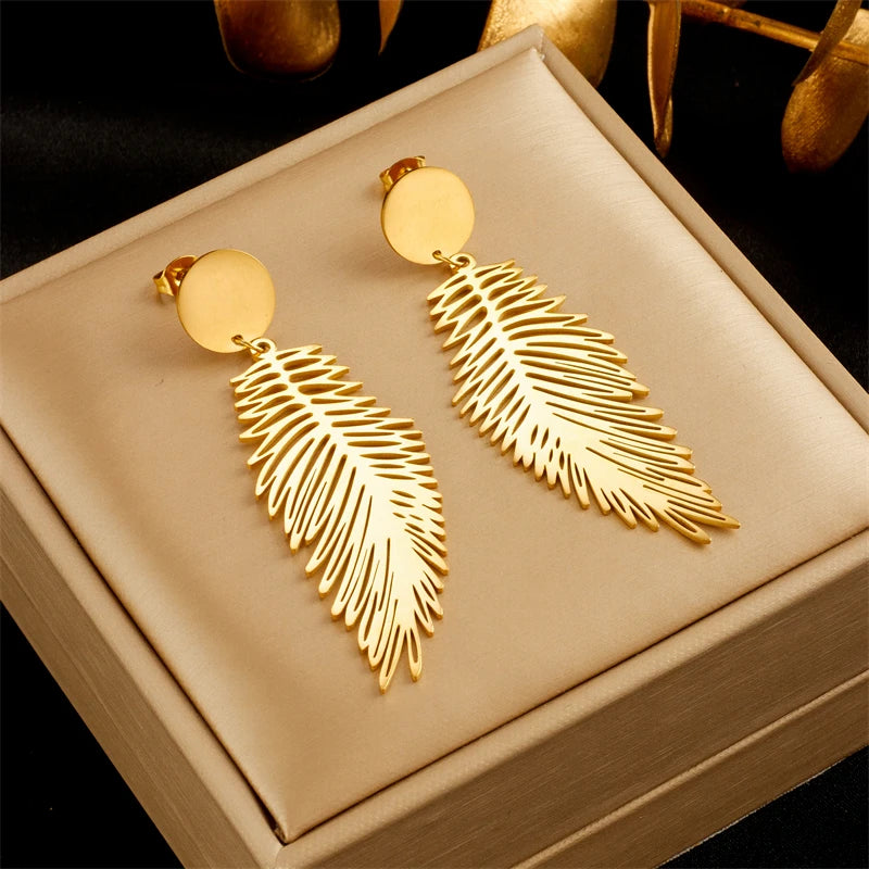 Gilded Plume Earrings in gold on a linen jewelry box